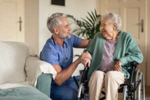 Older adult and family member organize labeled clothing, toiletries, and photographs in an assisted living room.