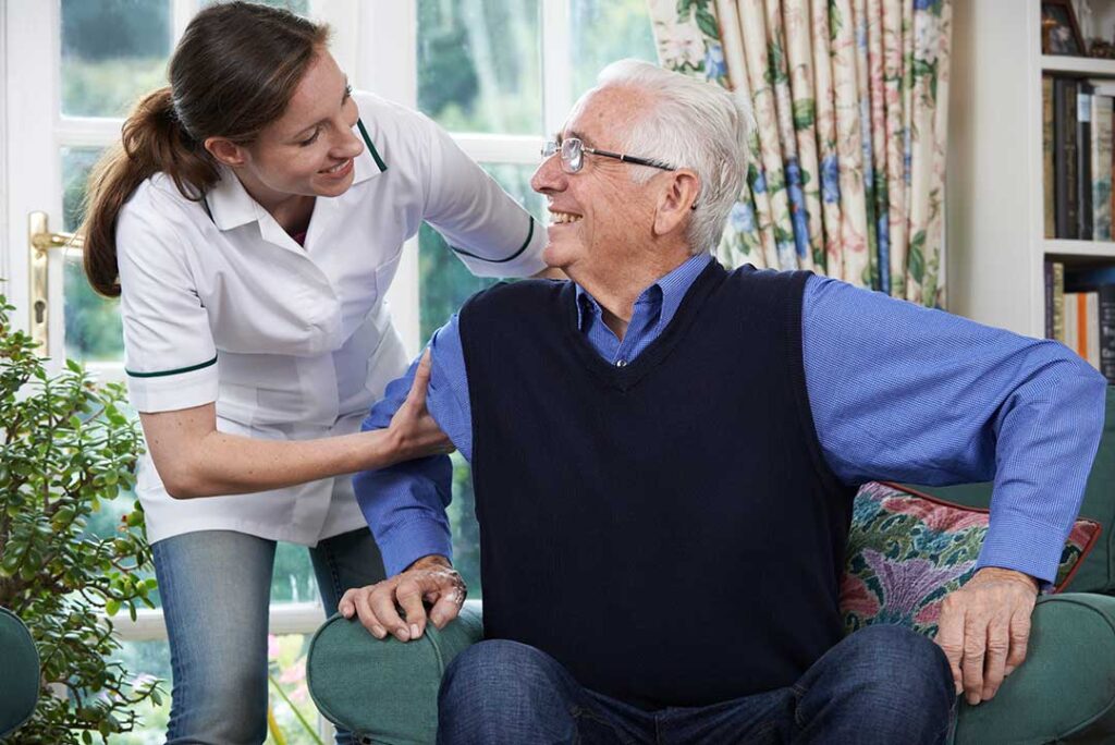 Adult children visiting and chatting with an elderly parent in a homey assisted living room setting.