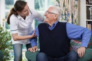Adult children visiting and chatting with an elderly parent in a homey assisted living room setting.